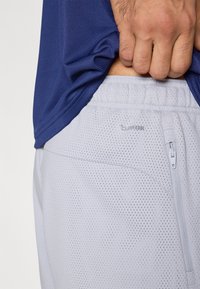 Ανοιχτό γκρι, διαπνέοντες σορτς από δίχτυ με φερμουάρ και λογότυπο "ClimaCool", συνδυασμένα με μπλε ναυτικό, υφασμένο αθλητικό τοπ.