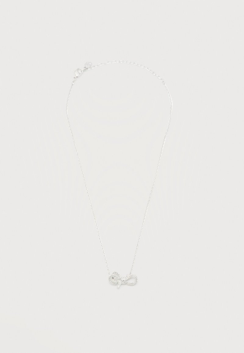 Collier chaîne délicate en argent avec un petit pendentif scintillant en forme de nœud centré sur un fond blanc uni.
