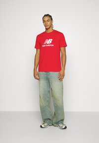 New Balance ESSENTIALS LOGO UNISEX - Nyomott mintás póló - team red