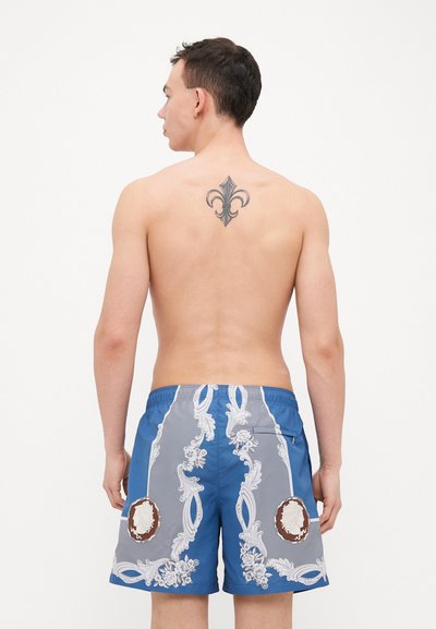 Shorts de bain pour hommes présentant un design bleu et gris avec des motifs floraux et des accents de médaillon. Fabriqués en tissu léger et respirant.
