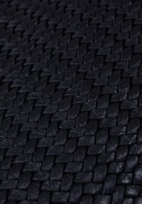 Woven black leather texture with a tight, intricate pattern, showcasing smooth, glossy surfaces and a durable appearance.
