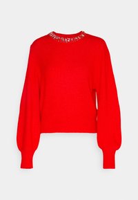 Punainen pitkähihaine neulepaita, jossa on kuppimaiset hihat ja pyöreä kaula-aukko, koristeltu hopeisilla niiteillä ja helmiäisillä.