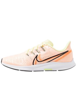 Jasnoróżowe buty do biegania Nike z czarnym logo Swoosh, białą podeszwą i neonowożółtymi akcentami, pokazane z boku na białym tle.