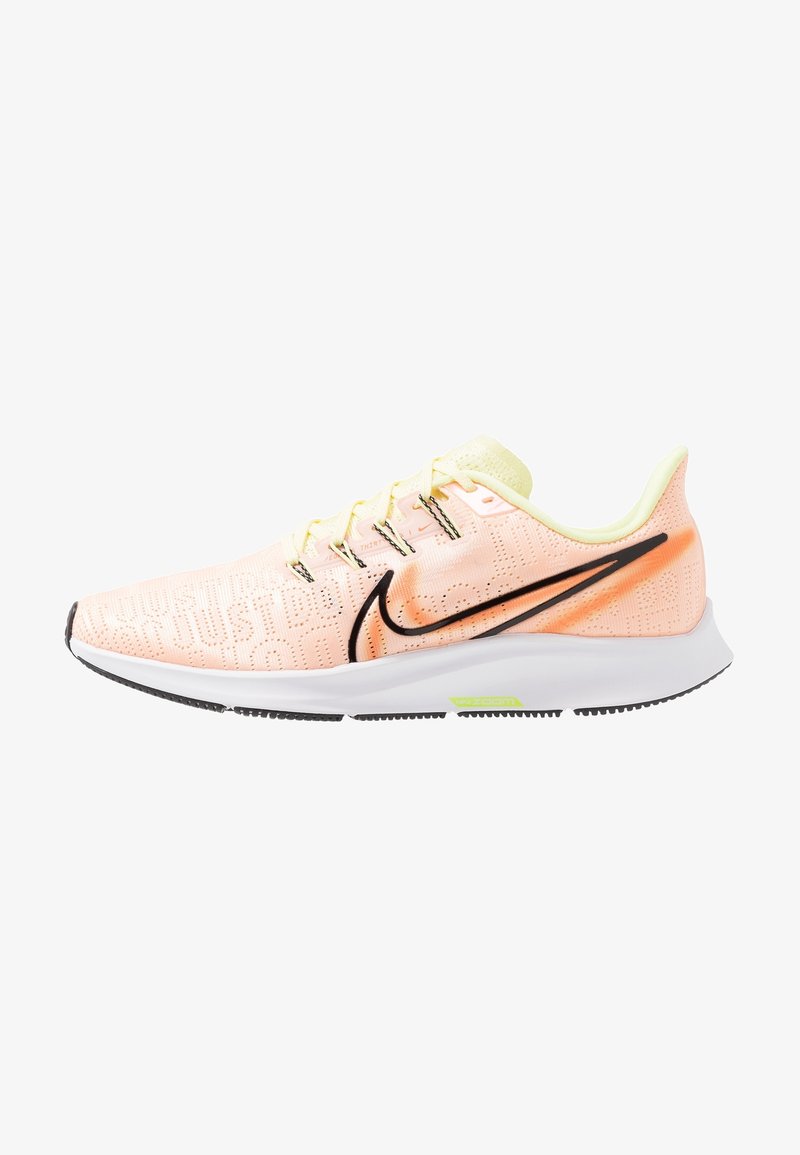 Chaussure de course Nike couleur pêche claire avec logo swoosh noir, semelle blanche et accents jaune néon, vue de côté sur fond blanc.