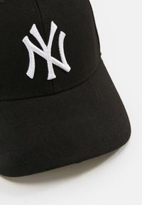 Casquette de base-ball noire en tissu avec une forme structurée. Présente un logo "NY" brodé en blanc sur le devant.