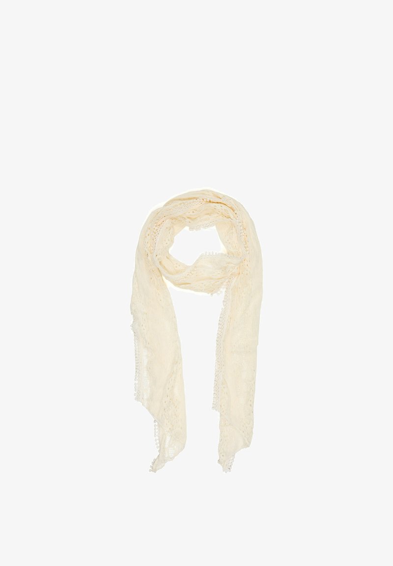 Écharpe en dentelle beige clair avec des motifs délicats et une bordure de petits pompons le long des bords, légèrement enroulée sur un fond blanc.