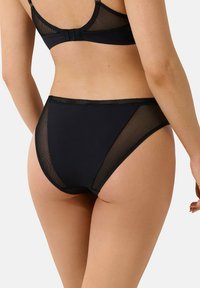 Zwart lingerieset met een mesh achterkant en een gebogen snit. De slip heeft een gladde stof aan de voorkant en mesh accenten aan de zijkanten.