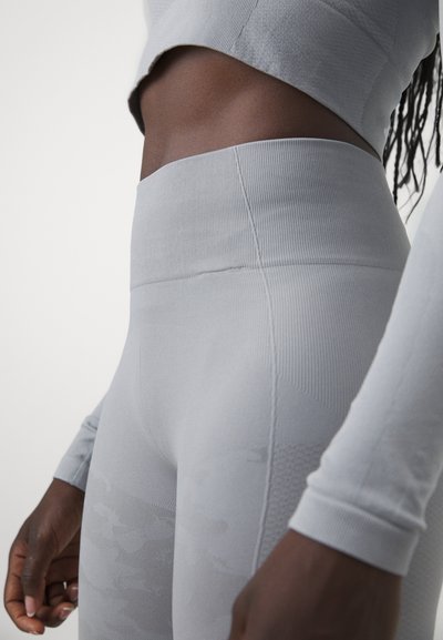 Leggings griși fără cusături cu talie înaltă și modele texturate. Materialul este ajustat pe corp, cu un finisaj neted și accente rigate.