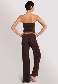 Bruine geribbelde bandeau top gecombineerd met bijpassende wide-leg broek. Soepele, rekbare stof met een constante textuur en een strakke pasvorm.