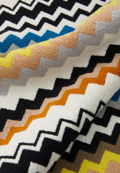 Flerfarget zigzag mønster tekstil med svarte, blå, gule, oransje, grå og hvite nyanser med en strukturert overflate. Myk og lugn.