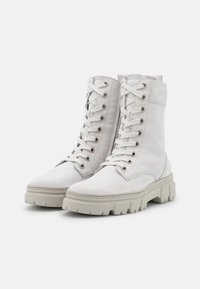 Botas de tobillo de cuero blanco con cordones y un collar acolchado, que cuentan con una suela texturizada y ojales de metal para los cordones, diseño limpio.