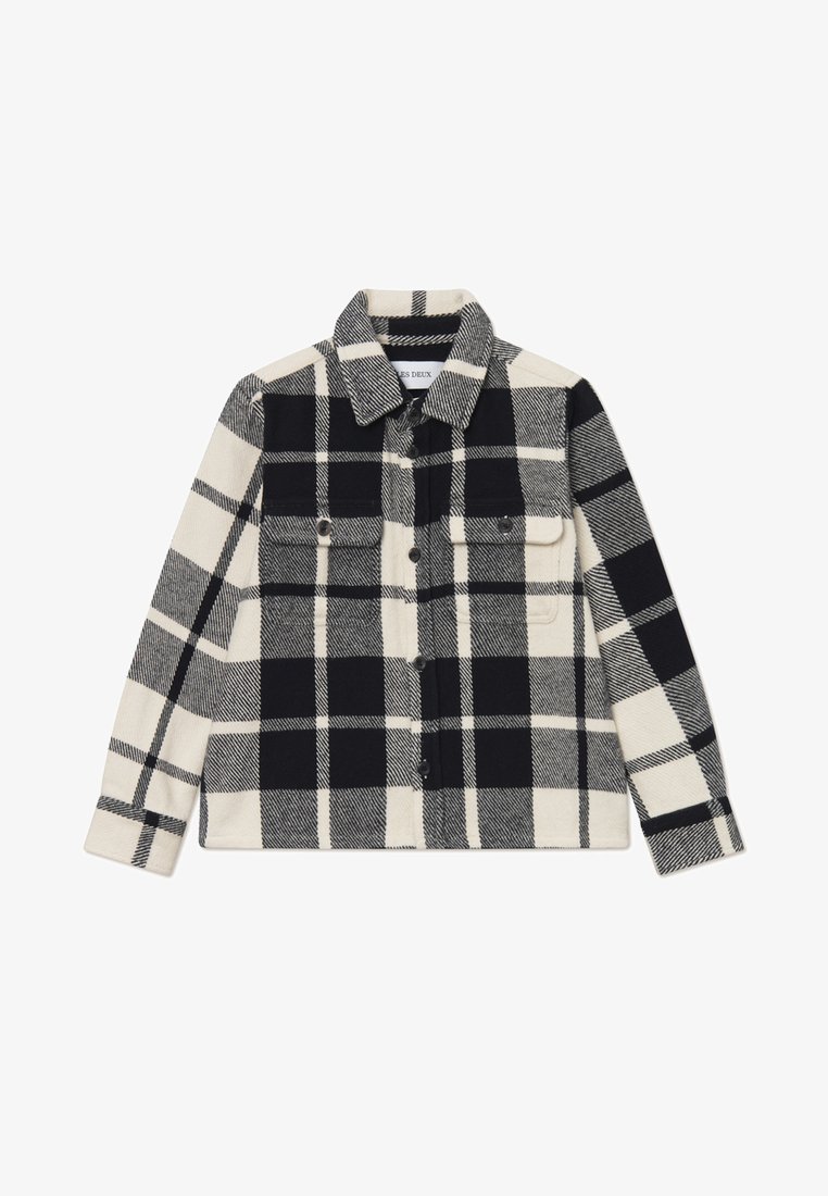 Camisa de flanela xadrez em preto e branco, com dois bolsos no peito, fecho de botões e colarinho. Textura suave e formato estruturado.