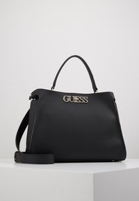 Sac à main en cuir noir à surface texturée, logo doré, poignées courtes et bandoulière amovible. Forme rectangulaire au design élégant.