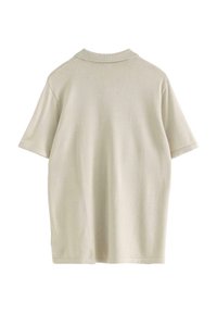 Beige kortärmad polo med en ribbad krage och mjuk, slät textur. Enkel, rak design utan synliga mönster eller detaljer.