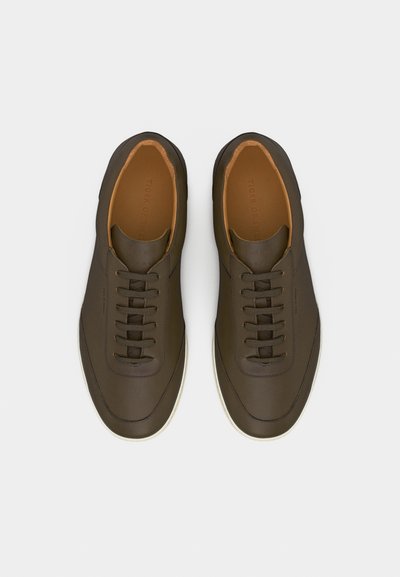 Para ciemnobrązowych, skórzanych, sznurowanych butów casual z białymi podeszwami, widzianych z góry na białym tle.