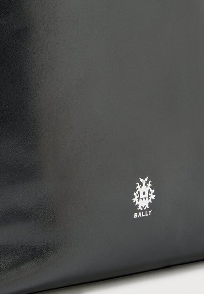 Black leather surface with a small white Bally logo featuring a crest and text near the bottom right corner.