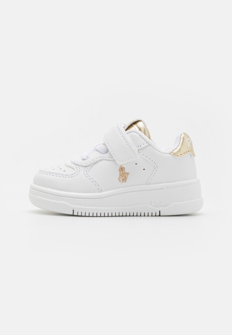 Baskets en cuir blanc avec un accent doré, dotées d'une sangle en Velcro et d'un design de bout perforé. Semelle en caoutchouc avec traction texturée.