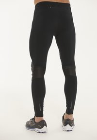 Svarta sportleggings med en åtsittande design, med nätpaneler vid knäna och reflexdetaljer. En säker dragkedjeficka finns på baksidan.