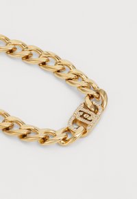 Hrubý zlatý náhrdelník s obdĺžnikovým zapínaním ozdobeným malými jasnými kryštálmi na svetlom pozadí.