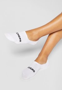 Balti potītes zeķes, izgatavotas no kokvilnas maisījuma, ar melnu "SKECHERS" logo virsotnē. Mīksta tekstūra un neredzamā dizains.