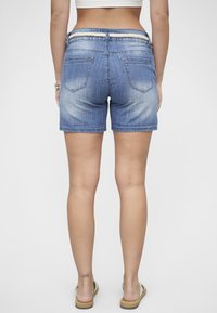 Shorts en denim avec un dégradé bleu clair, dotés d'une ceinture en corde, de deux poches arrière et d'un ourlet juste au-dessus de la cuisse.