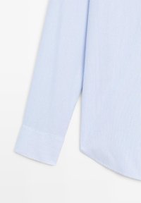 Camicia a righe blu e bianche, a maniche lunghe con orlo arrotondato, realizzata in cotone liscio e con polsini ben definiti. Messa in risalto da sottili righe.