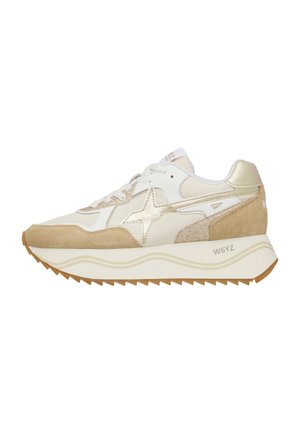 Scarpa da ginnastica beige e bianca con dettagli in pelle scamosciata e metallici, suola spessa con motivo ondulato e logo del marchio sul lato e sul tallone.