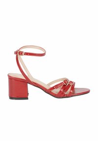 Sandali con tacco in pelle patinata rossa, dotati di tre cinturini sottili con fibbie dorate. Il tacco a blocco misura circa cinque centimetri.