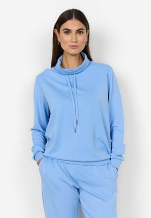 Pullover azzurro chiaro con alto collo a pipistrello, maniche lunghe e dettaglio con cordino. Tessuto morbido, vestibilità rilassata, abbinato a pantaloni coordinati.