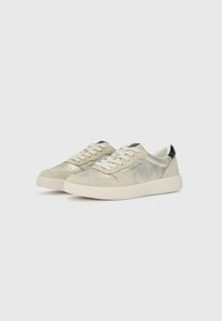 Sneakers grigio chiaro con un mix di tessuti lisci e scamosciati, lacci bianchi e un'accento nera sul tallone. Dettagli perforati sulla punta.