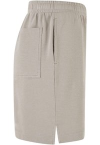 Jupe beige clair longueur genou avec taille élastique, fente latérale et une grande poche rectangulaire sur le côté gauche.