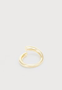 Anillo de metal en tono dorado con una superficie lisa y pulida. Diseño abierto con extremos redondeados, que presenta un pequeño grabado de logo en uno de los lados.