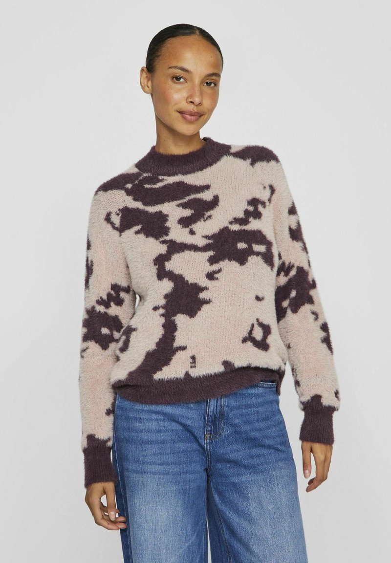 Pull encolure ras du cou en rose pâle et violet foncé, texture duveteuse avec motif abstrait, coupe décontractée, bords côtelés aux poignets et en bas, associé à un jean bleu.