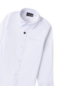 Camicia bianca a maniche lunghe con colletto ripiegato, chiusura frontale con bottoni, una tasca e un piccolo dettaglio con bottone nero. Realizzata in tessuto liscio.