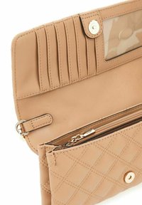 Portefeuille en cuir matelassé beige avec plusieurs fentes pour cartes, une fenêtre ID transparente et une poche zippée pour les pièces. Équipé d'accessoires en métal doré.