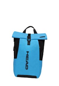 Sac à dos bleu à rabat, fabriqué en matière durable. Il possède des côtés en maille noire, une fermeture à boucle et le logo "HEAD" en lettres noires gras.