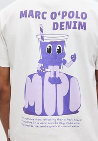 Μωβ καρτουνίστικο σμούθι με μάτια και άκρα που κρατάει μούρα, κάθεται πάνω σε μεγάλα στυλιζαρισμένα γράμματα "MOPD" με το κείμενο "MARC O'POLO DENIM" από πάνω.