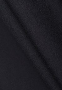 Közelkép szorosan szőtt fekete szövetből, amely finom átlós redőket mutat, kiemelve a textúrát és a finom varrás részleteit.