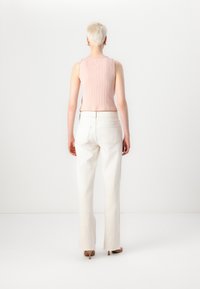 Light pink ribbed sleeveless top paired with high-waisted white straight-leg pants, featuring a smooth texture and subtle stitching details.