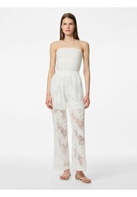 Haut sans bretelles blanc et pantalon fluide blanc avec des détails en dentelle et des motifs floraux. Texture douce, design à jambe large et taille élastique.