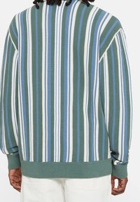 Knitted sweater featuring vertical stripes in green, blue, and white. Ribbed hem and cuffs with a relaxed fit and textured fabric.