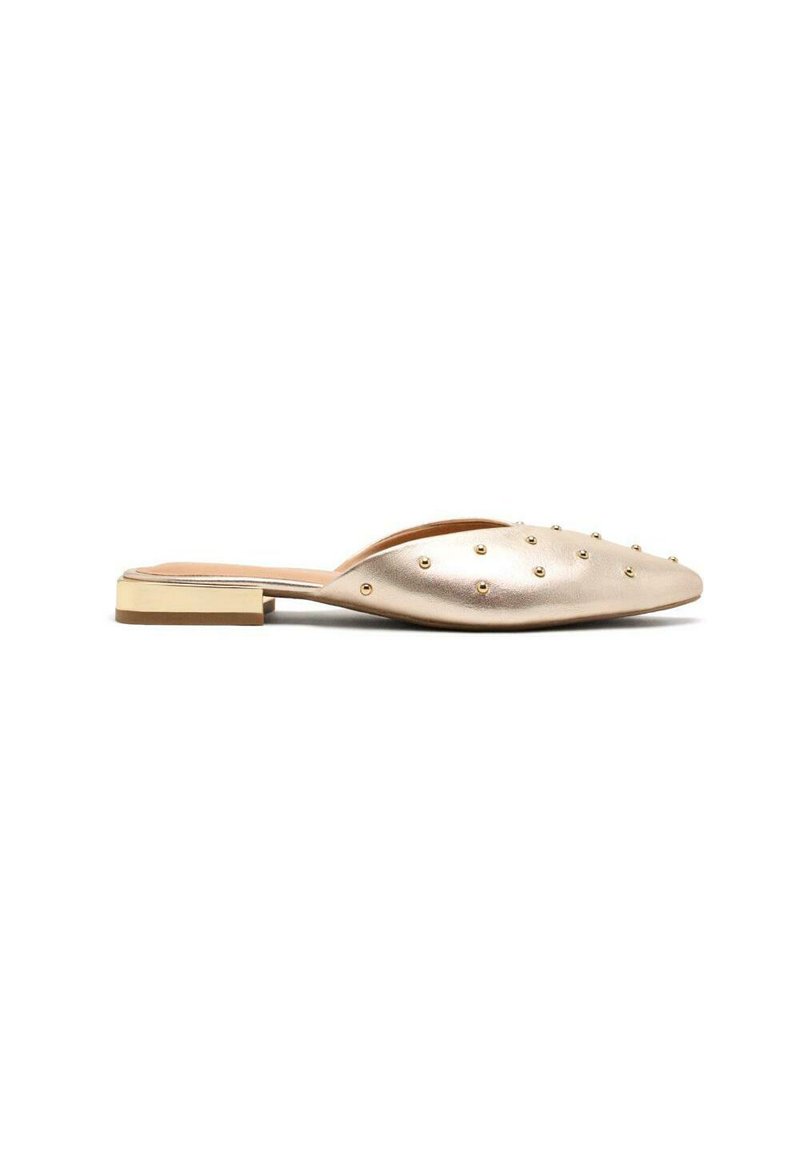 Zapato tipo slip-on de cuero dorado con punta afilada, tacón plano y adornos de tachuelas en la parte superior. Diseño minimalista con un acabado elegante.