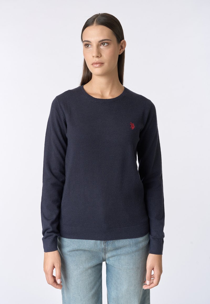 Maglione lavorato a maglia blu navy con maniche lunghe e scollo rotondo; presenta un piccolo logo rosso sul petto e polsini e orlo a coste.
