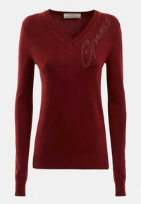 Pull en maille bordeaux avec col en V, manches longues et détails à clous métalliques formant le mot « Guess » sur le devant. Poignets et ourlet côtelés.