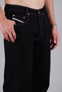 Black denim jeans feature a straight-leg design, copper accents, and contrasting white stitching. Front pocket detail visible.