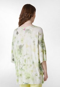 Lätt, flödande skjorta i vitt med gröna blommönster,vida ärmar och rundad halsringning. Har en liten rosa etikett bak.