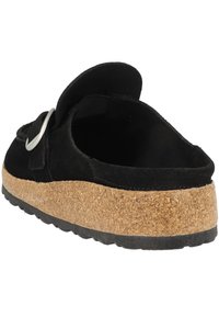 Svart mocka slip-on sko med korkmellansolo och gummiyttersula, med en silverfärgad spänne och elastisk rem för en säker passform.