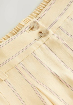 Tejido beige con rayas verticales rosa y azul. Presenta pliegues y dos botones redondos y transparentes en la cintura con un detalle de borde rizado.