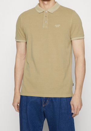 Polo color caqui con textura suave, tapeta de tres botones, mangas cortas y cuello en contraste. Pequeños detalles de logotipo en el pecho.