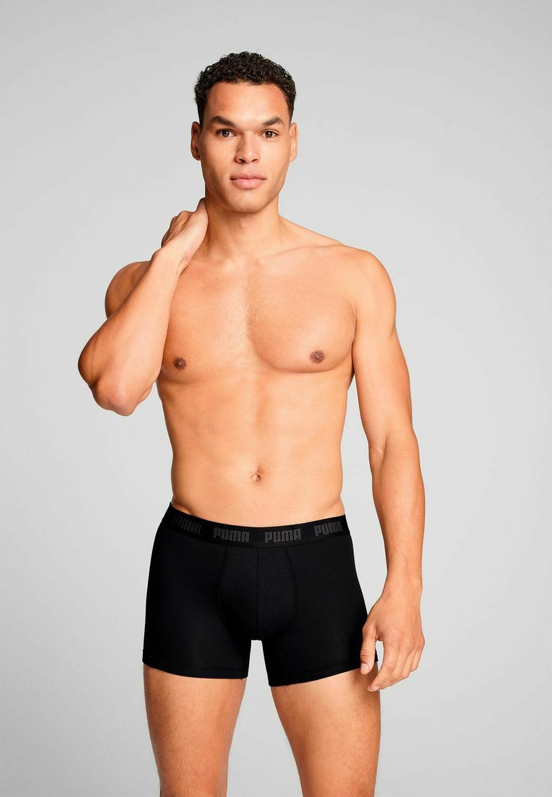 Men's black boxer briefs made of smooth fabric with a wide elastic waistband featuring the Puma logo. Fitted design and mid-thigh length.
